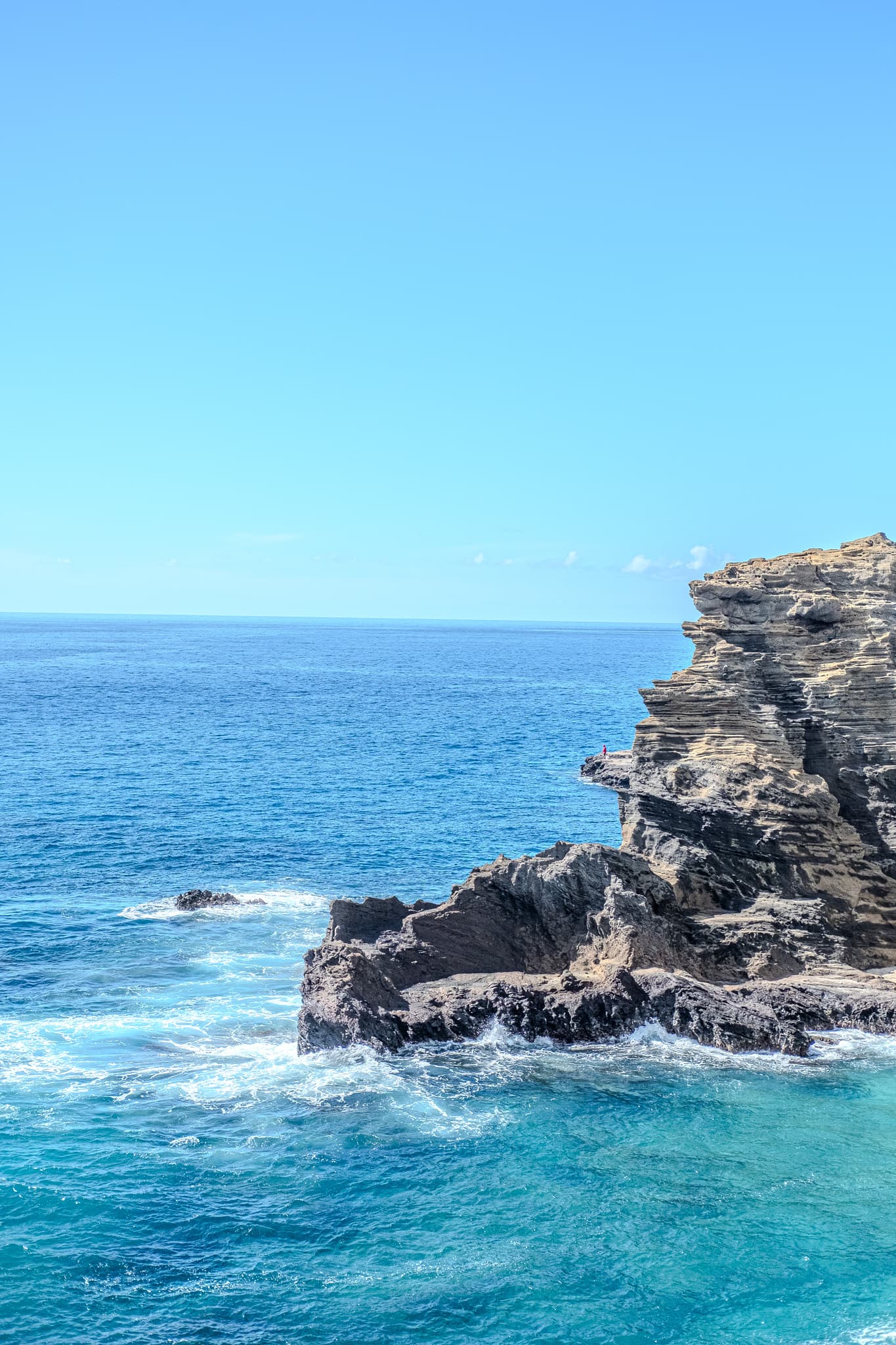 Waves breaking on dark rocks under a clear sky