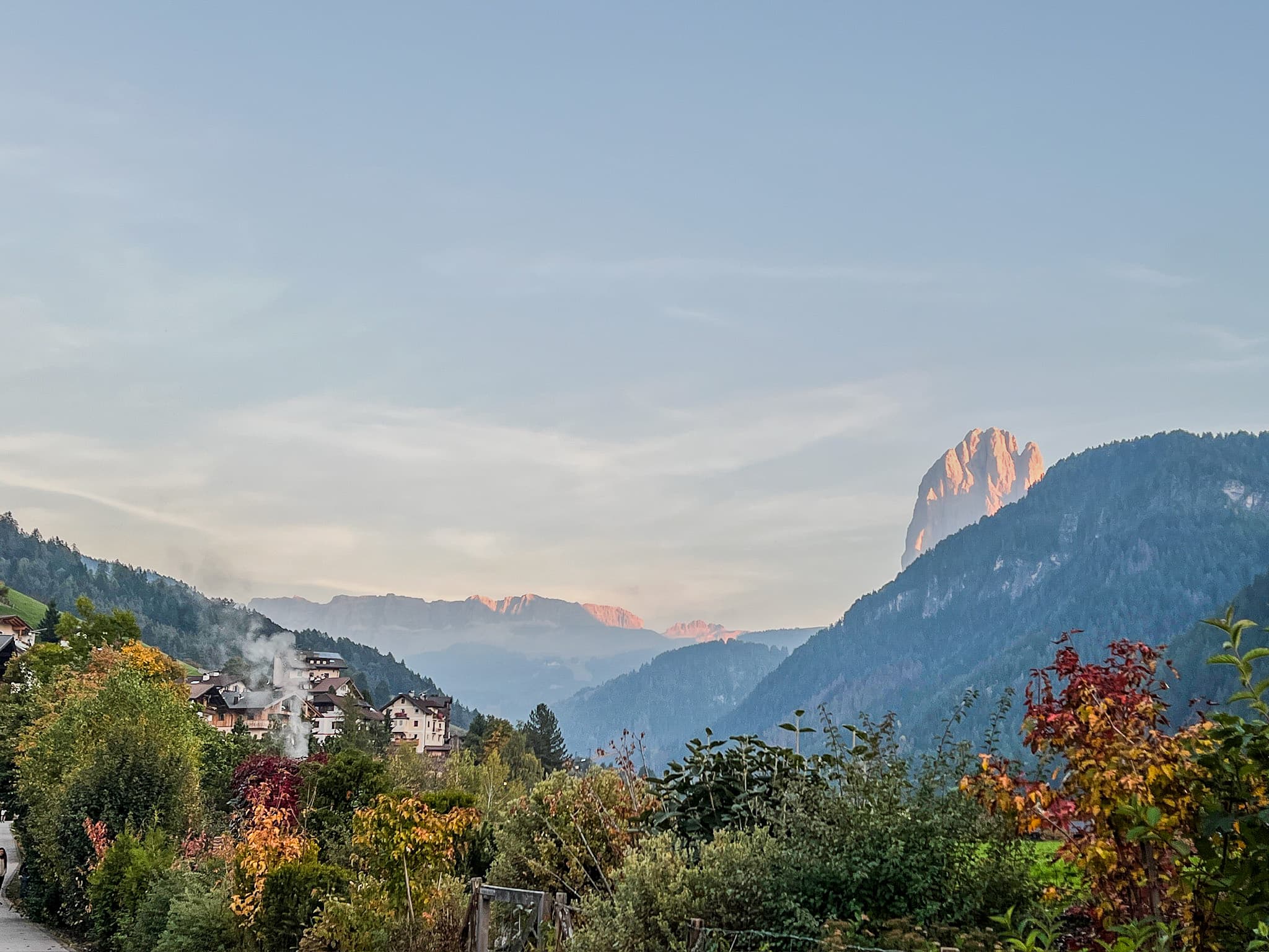 Autumn trees below a pink-lit mountain peak