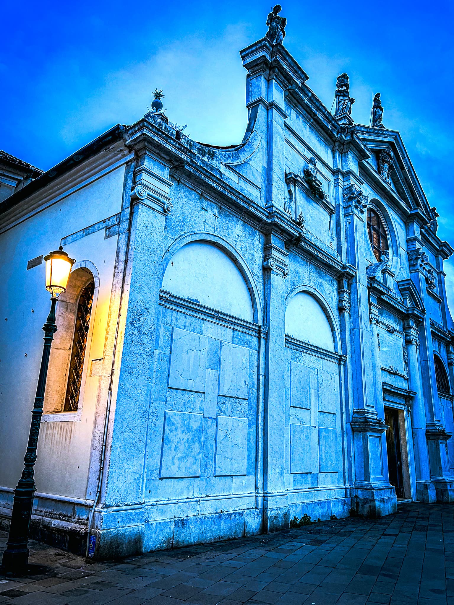 Lamplit church facade under a deep blue evening sky