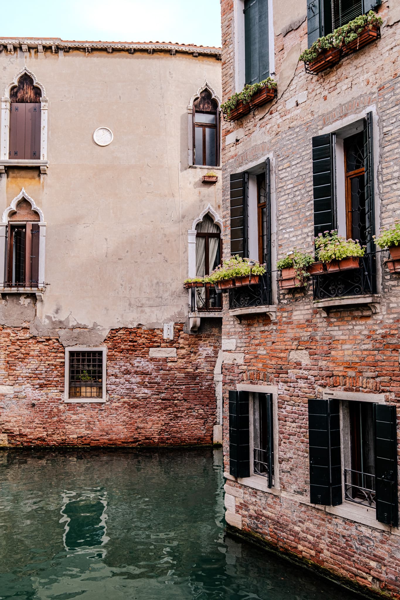 Brick and stucco houses with flower boxes above a canal