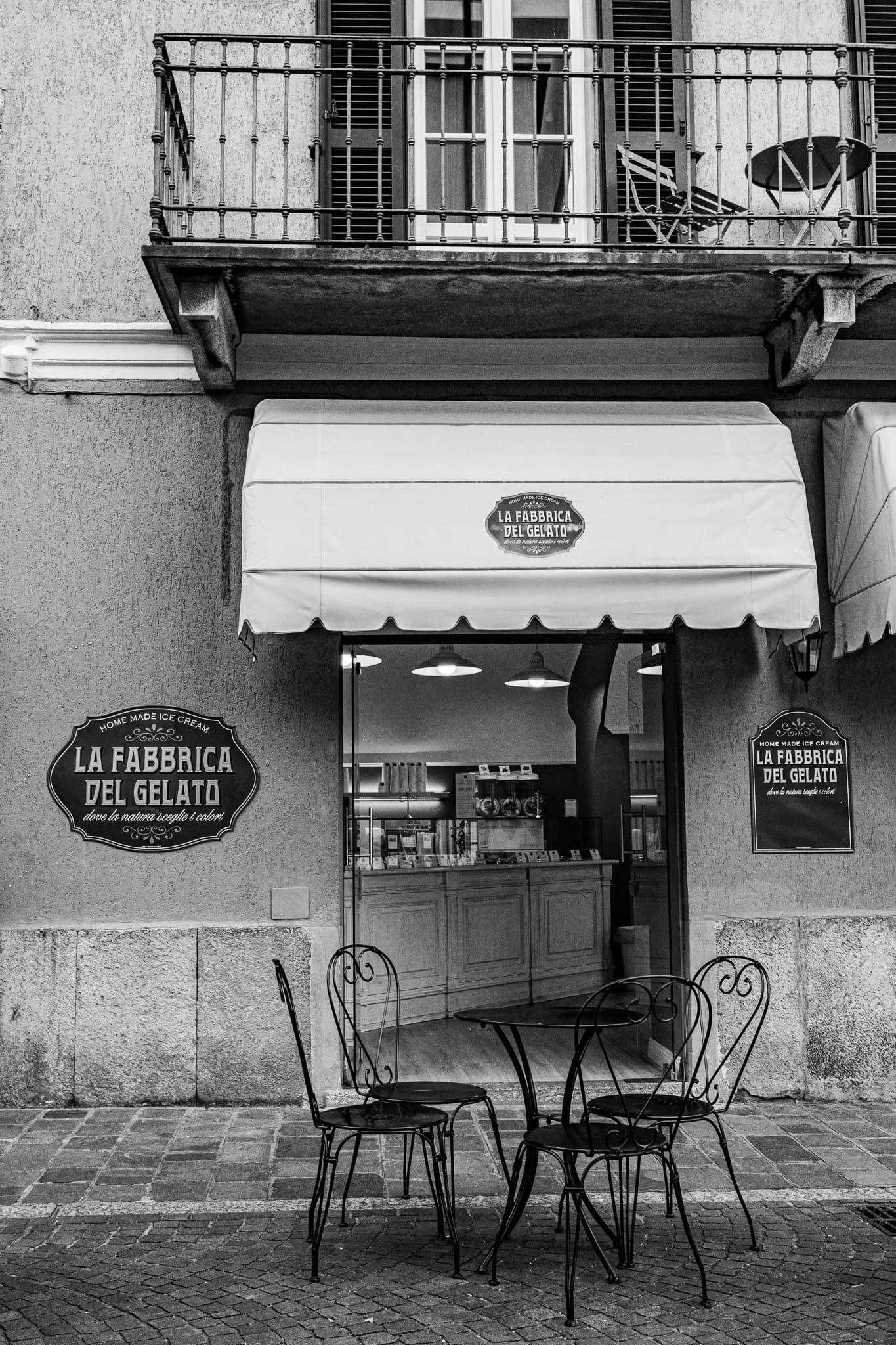 Gelato shop with iron chairs beneath a white awning