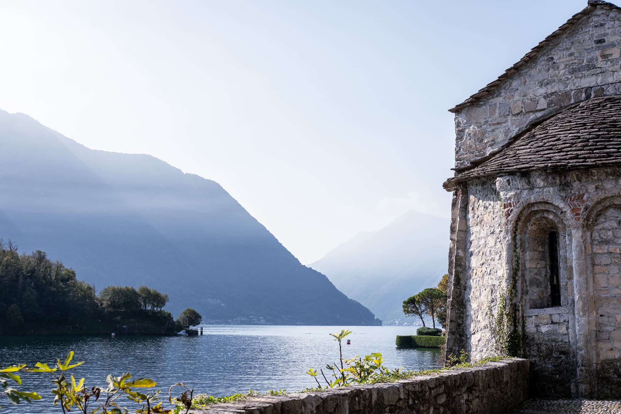 Old stone chapel above the lake in hazy morning light
