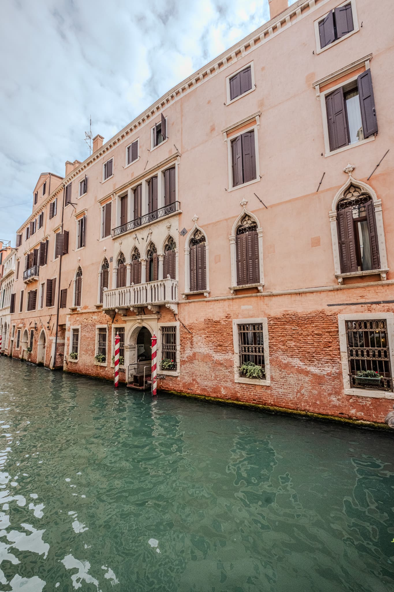 Pink palazzo with striped mooring poles along a canal
