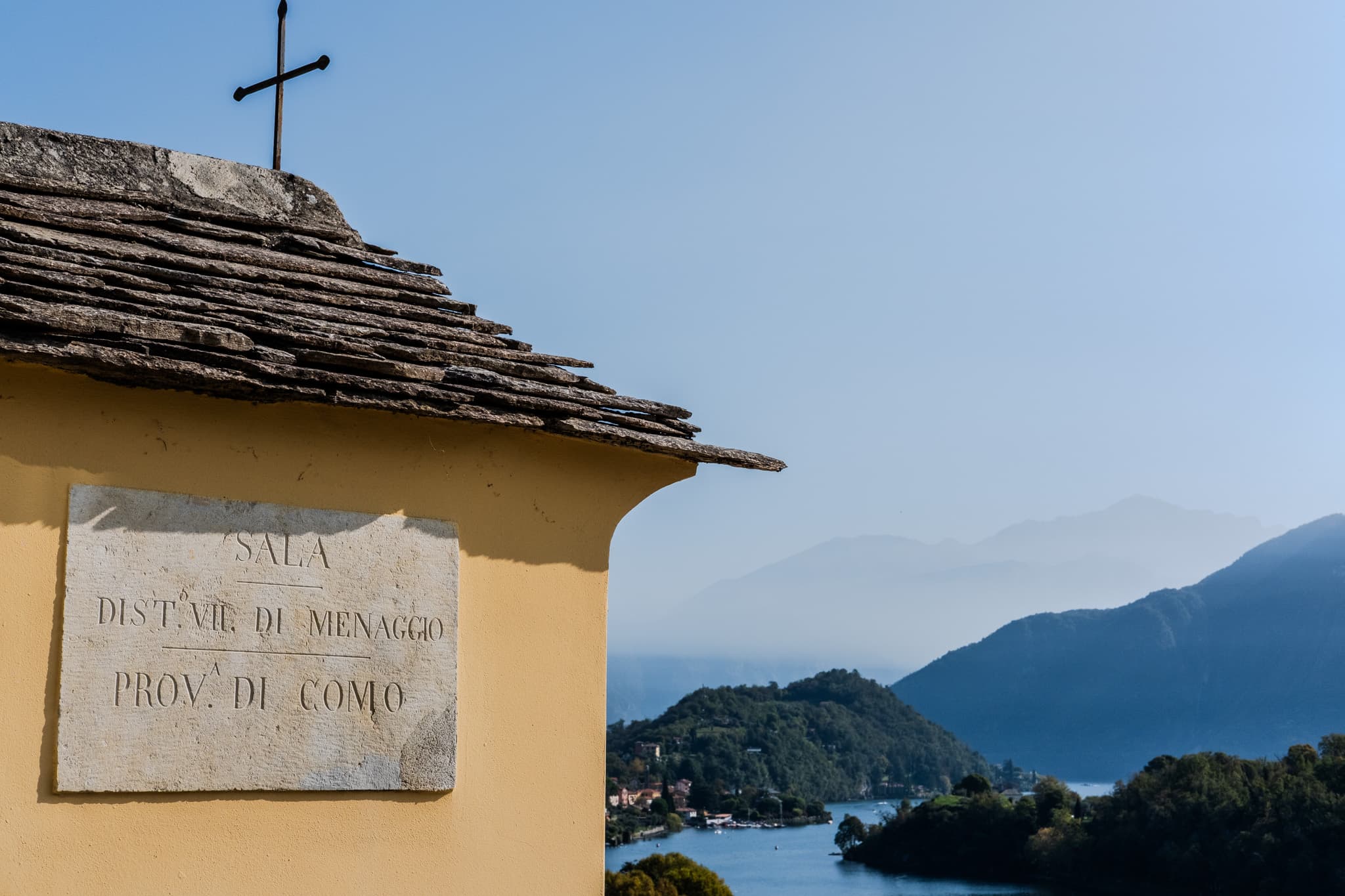Yellow chapel wall with a carved plaque above the lake