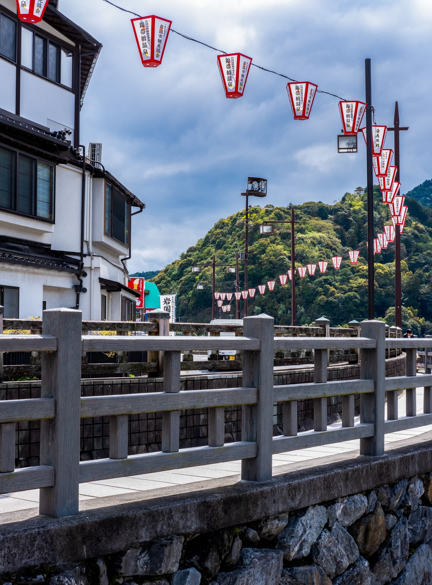 Red lanterns strung above a riverside street