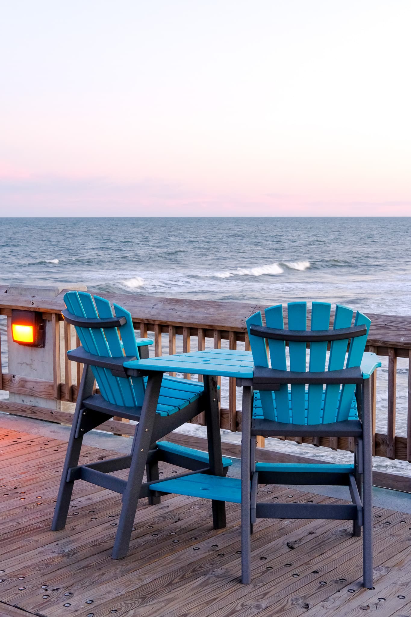 Two blue chairs on a deck overlooking the ocean