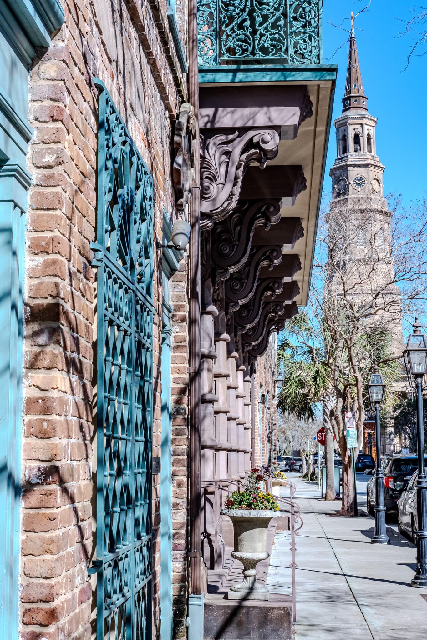 Brick wall and iron gate below a church steeple