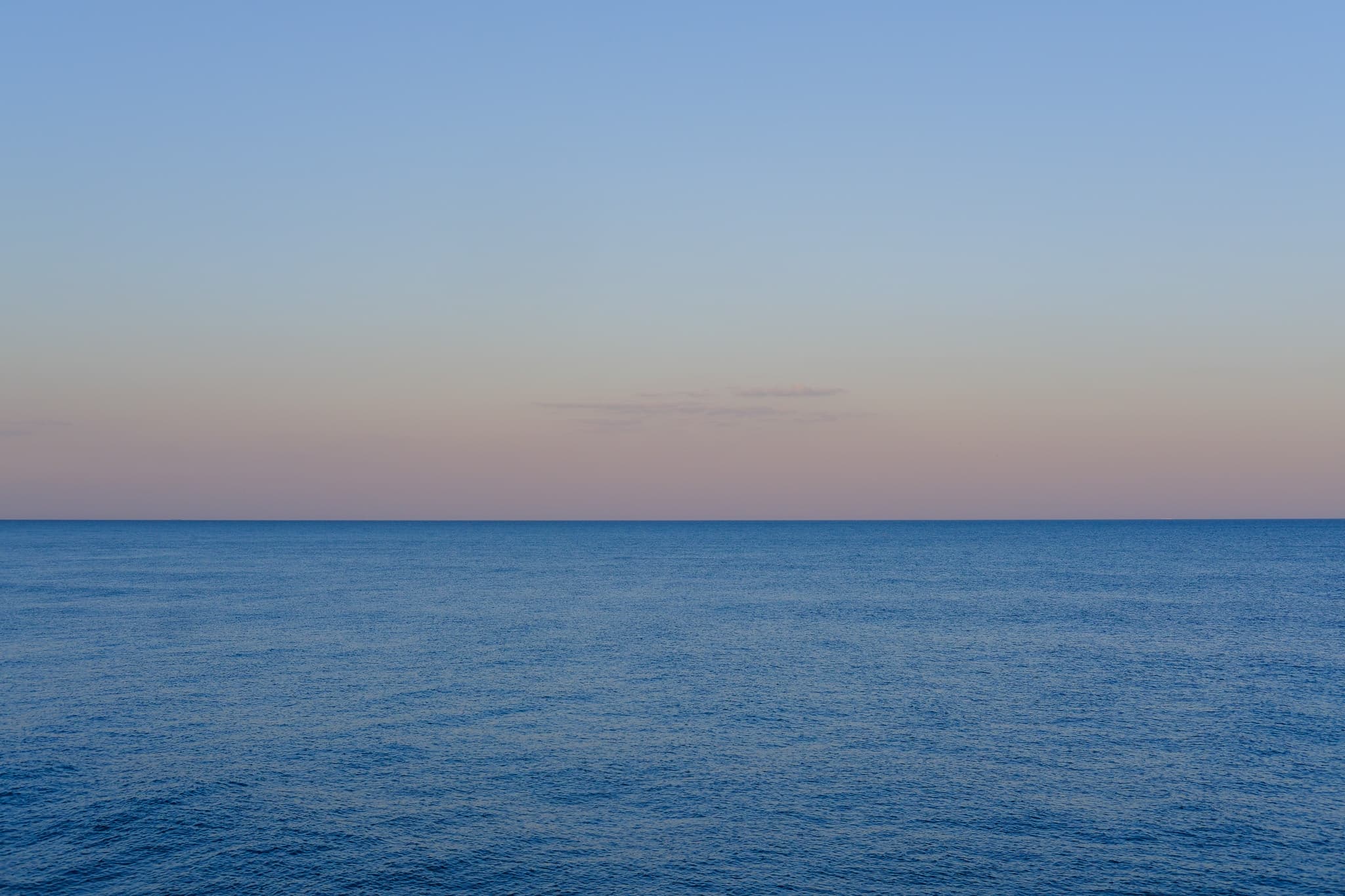 Calm ocean horizon under a pastel evening sky