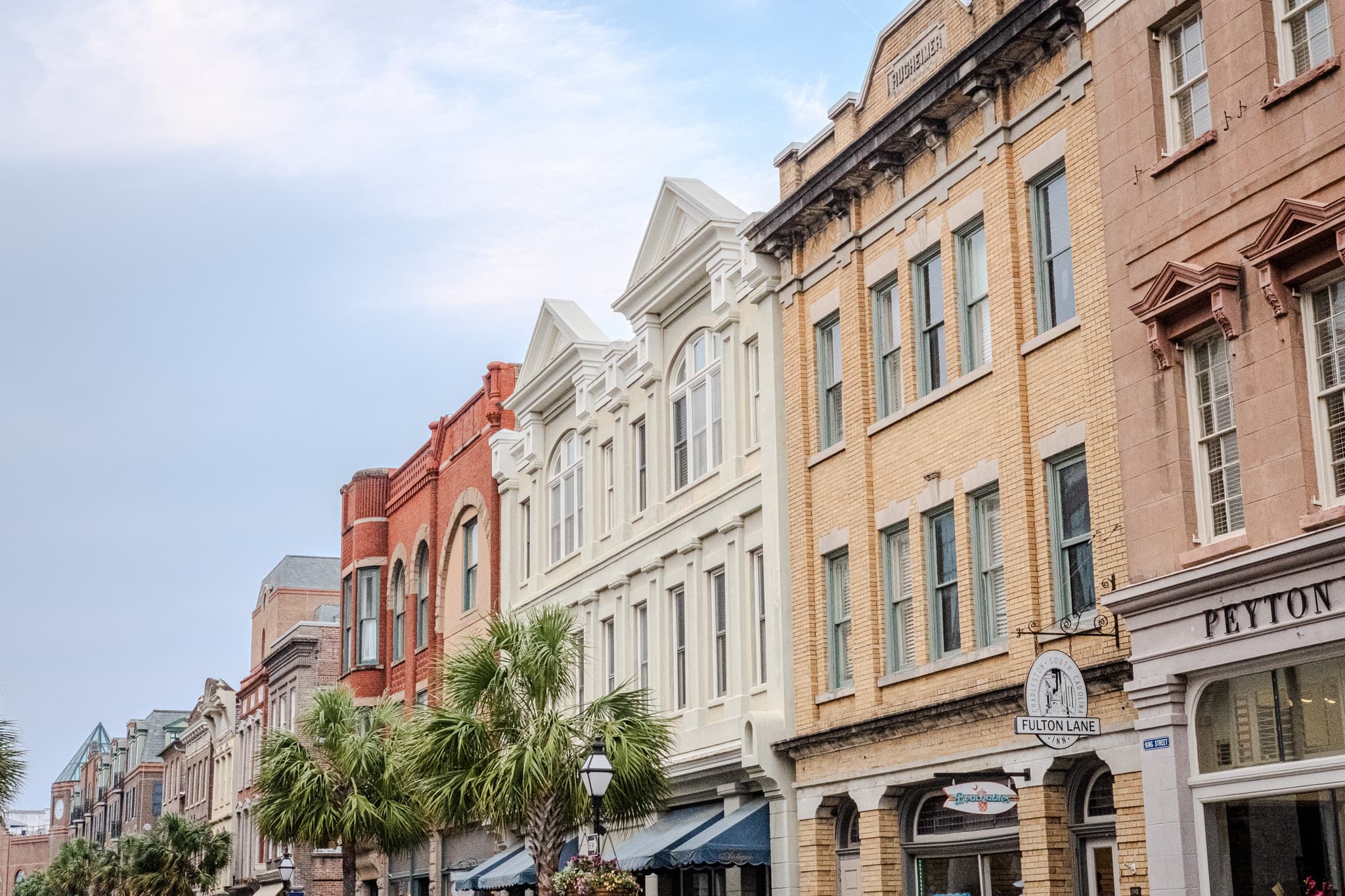 Pastel storefronts along a palm-lined street