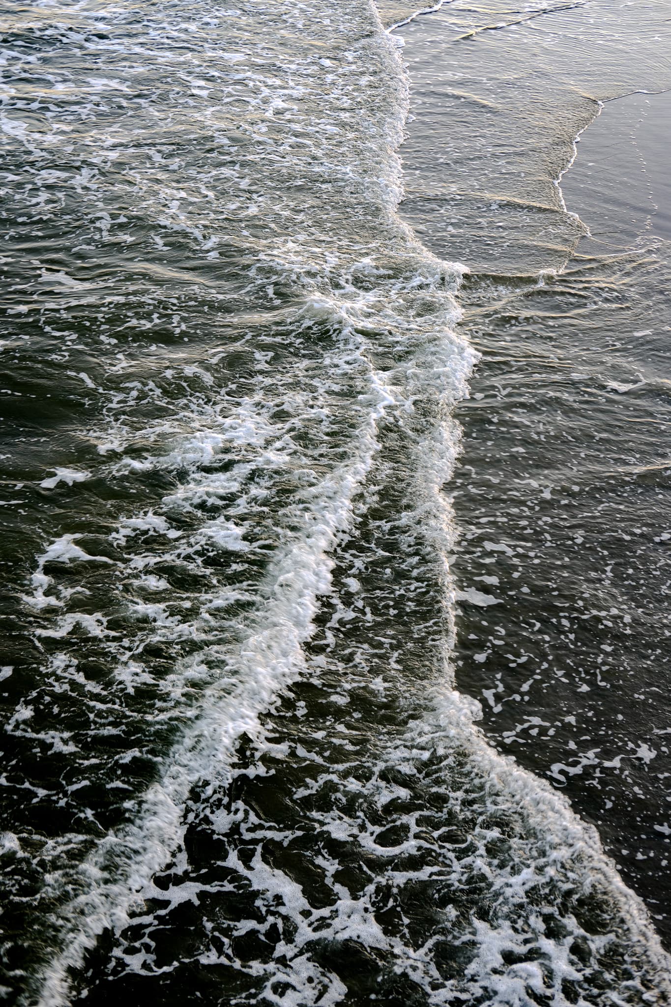 Lines of sea foam crossing on the shore, seen from above
